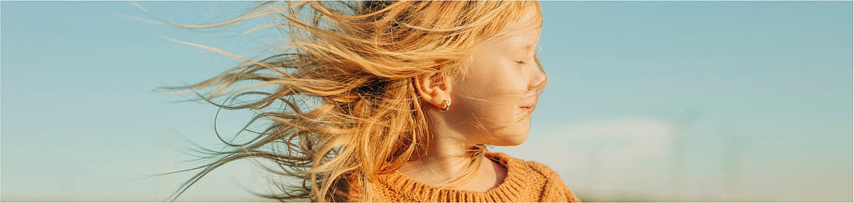 Ohrenschmerzen bei Kindern - Mädchen im Wind mit gelbem Pullover