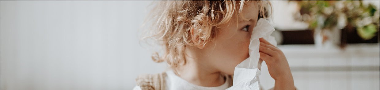 Headerbild – Kind mit Taschenbuch: Schnupfen bei Kindern