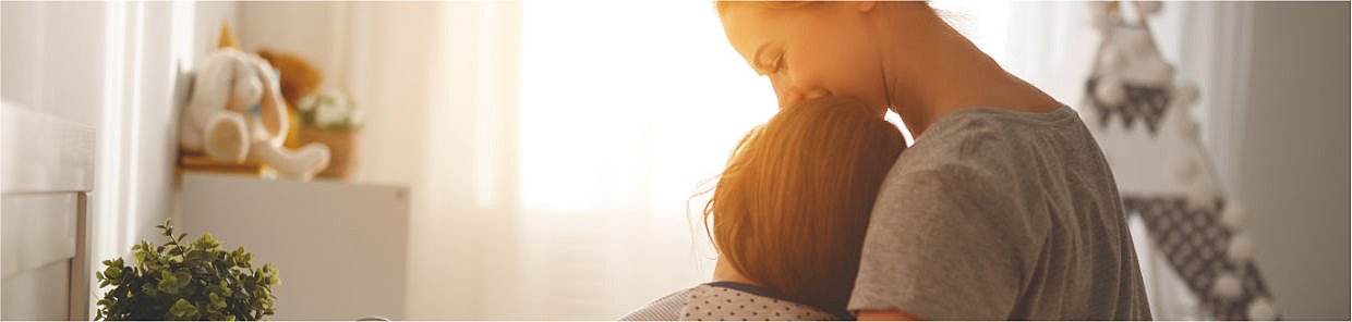 Mutter tröstet krankes Kind im Kinderzimmer