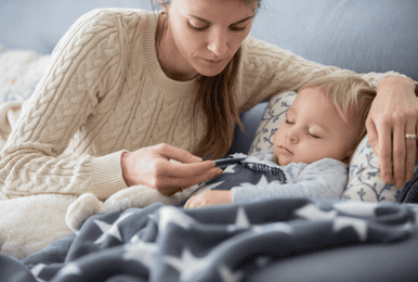 Mutter liegt mit krankem Kind im Bett